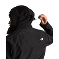 Modelo de espaldas ajustando el cordón de la capucha de la chaqueta The North Face Carto Mono Triclimate negra, con el logotipo bordado en la espalda y el puño con velcro.