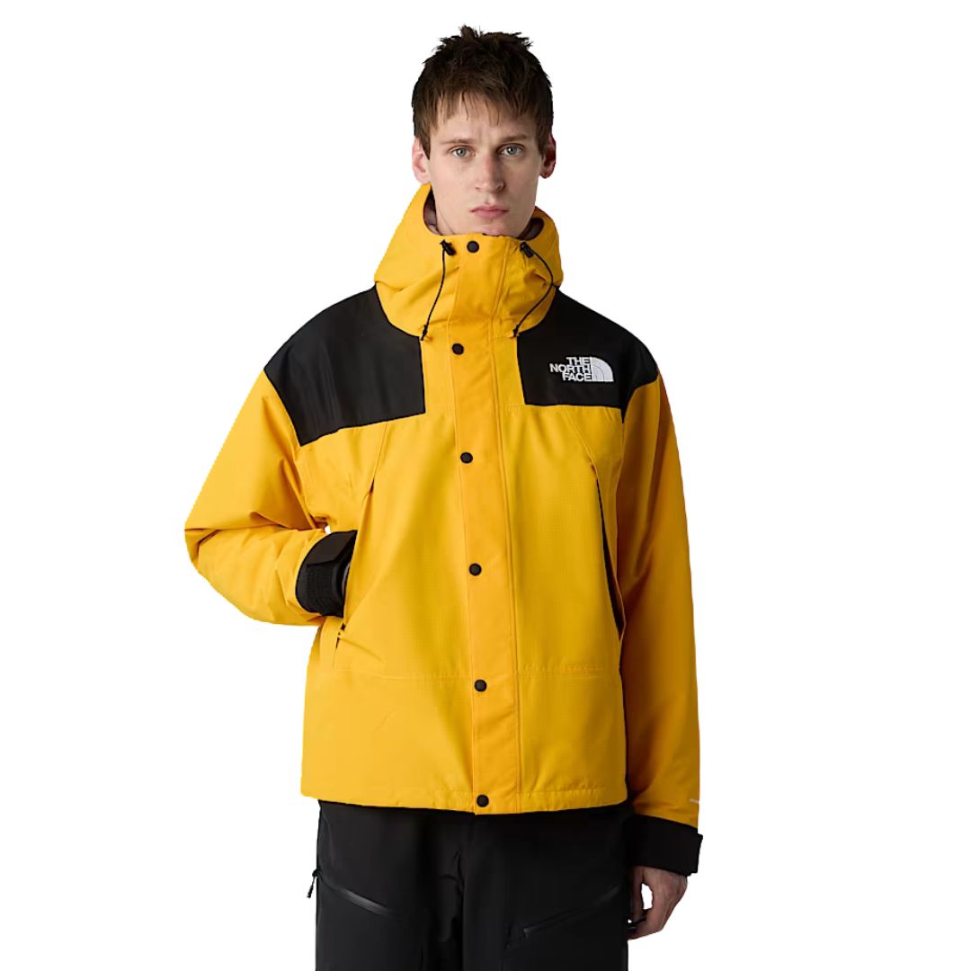 Modelo vistiendo chaqueta The North Face Dryvent Mono Mountain Summit Gold y negro TNF cerrada, vista frontal de cuerpo entero.