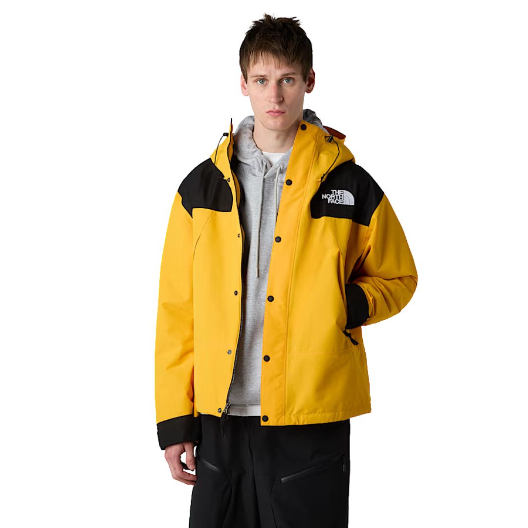 Modelo con chaqueta The North Face Dryvent Mono Mountain Summit Gold y negro TNF abierta sobre sudadera gris, vista frontal.