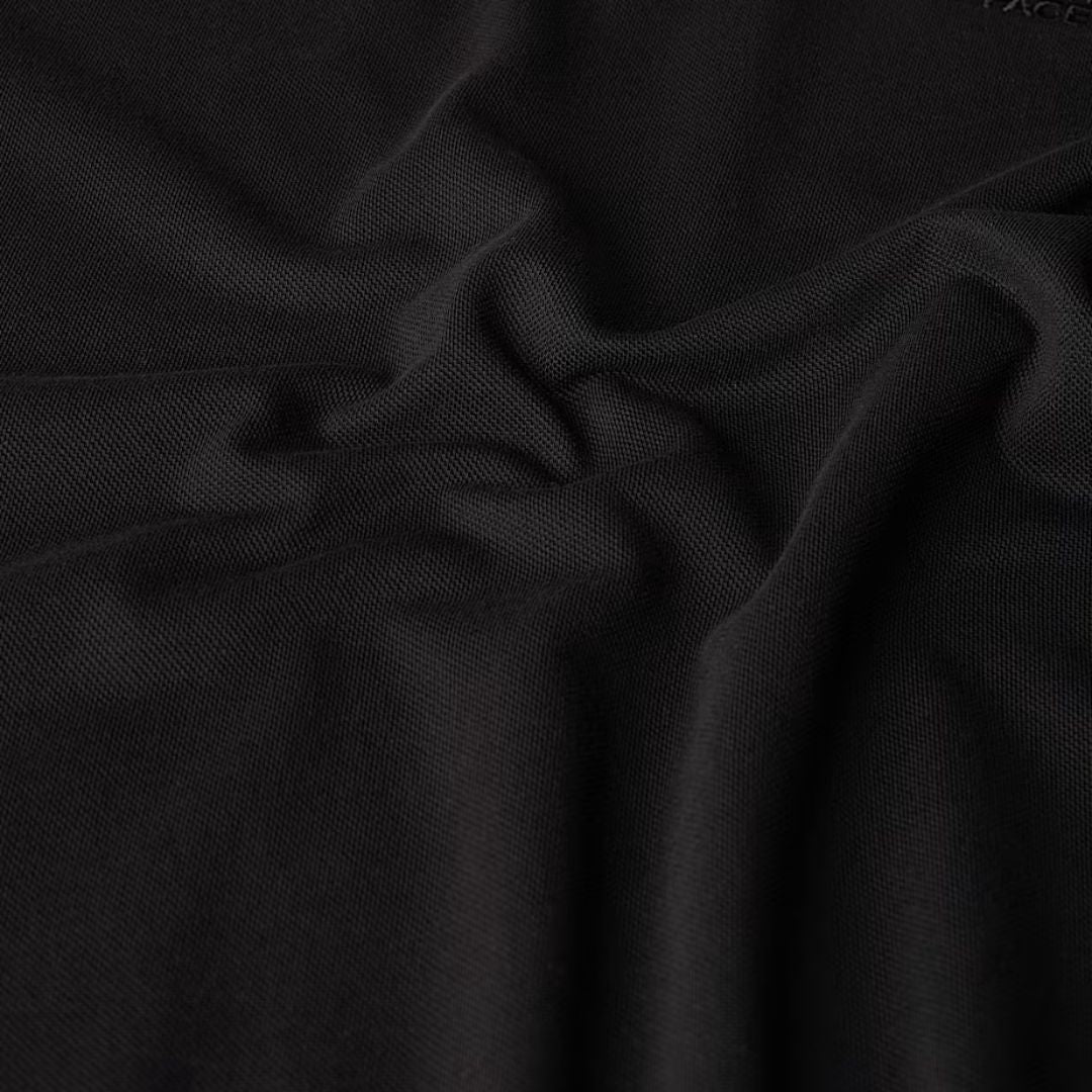 Detalle del tejido piqué negro del polo The North Face Essential Polo Tee.