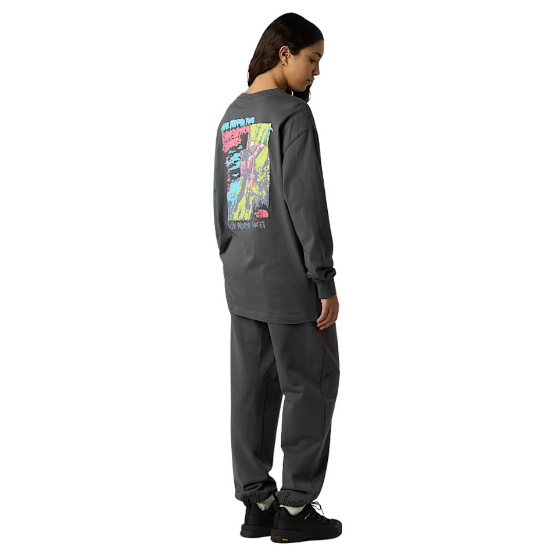 Modelo de perfil vistiendo camiseta The North Face Expedition Celebration en color anthracite grey, destacando el ajuste holgado.