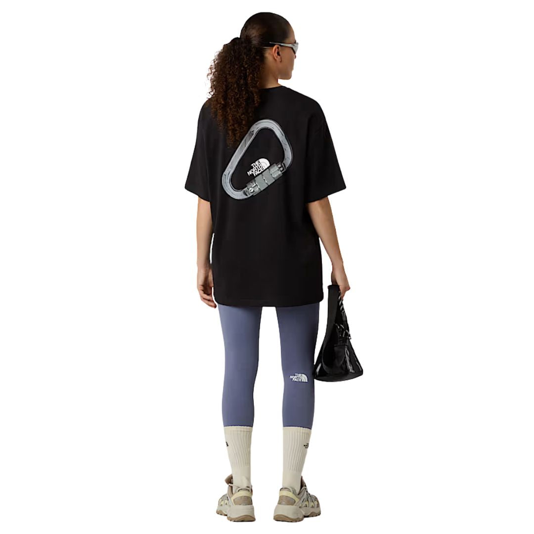 Vista trasera de la camiseta The North Face Explore Carabiner Relaxed Tee en negro, llevada por modelo mujer con leggings.