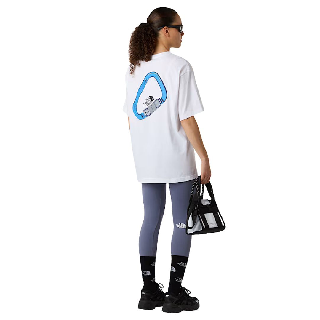 Mujer de espaldas con la camiseta The North Face Explore Carabiner Relaxed Tee blanca y gráfico de mosquetón azul en la espalda.