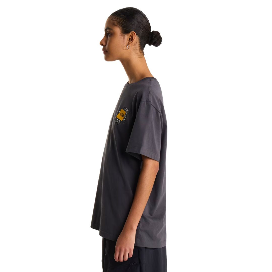 Camiseta The North Face Gear Up Get Out RLX en gris antracita puesta en modelo mujer, vista lateral de perfil mostrando el corte holgado y la caída de la manga.