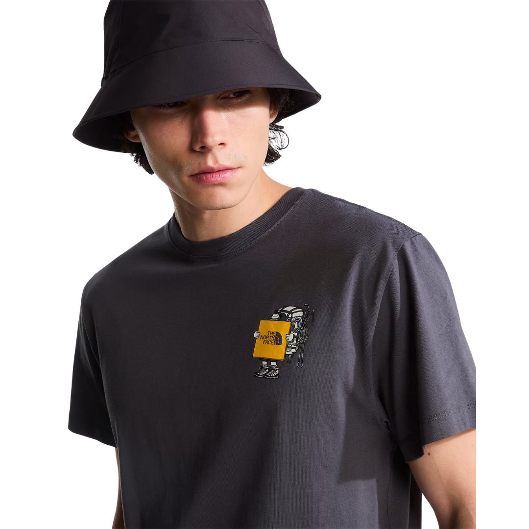 Camiseta The North Face Gear Up Get Out RLX en gris antracita puesta en modelo hombre, primer plano del gráfico pequeño del mochilero con logo amarillo/mostaza en el pecho, con sombrero de pescador a juego.