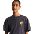 Camiseta The North Face Gear Up Get Out RLX en gris antracita puesta en modelo mujer, primer plano del cuello y el gráfico pequeño del mochilero con logo amarillo/mostaza en el pecho.