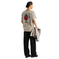 Camiseta The North Face Gear Up Get Out RLX en color piedra en modelo mujer de cuerpo entero por detrás, con sudadera a juego en la mano, luciendo el gráfico trasero completo.