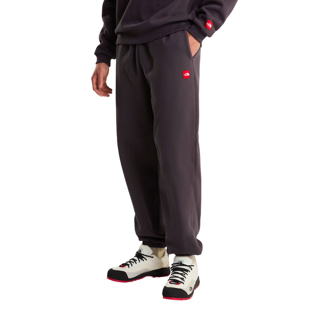 Detalle lateral en modelo del pantalón de chándal Red Box de The North Face en color Obsidian, con el parche bordado Red Box visible junto al bolsillo para las manos.