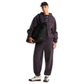Look completo en modelo con el pantalón de chándal Red Box de The North Face en color Obsidian, combinado con sudadera con capucha, gorra y bolso tote de la marca.