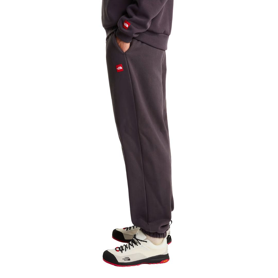 Vista lateral en modelo del pantalón de chándal Red Box de The North Face en color Obsidian, mostrando el bolsillo lateral con el parche bordado Red Box y el corte relajado.