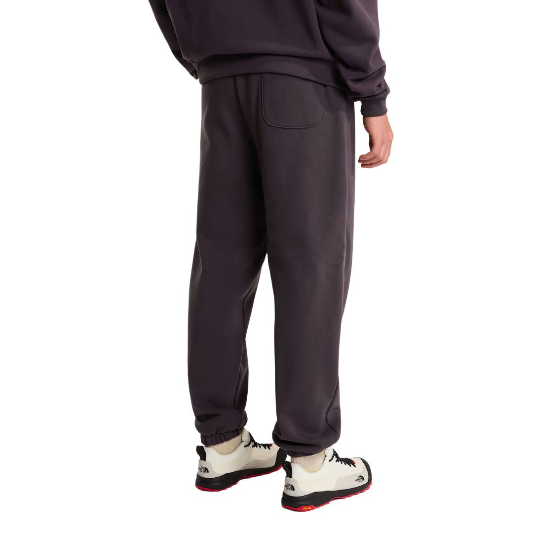Vista trasera en modelo del pantalón de chándal Red Box de The North Face en color Obsidian, combinado con sudadera a juego y zapatillas de senderismo The North Face.