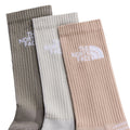 Pack de 3 calcetines The North Face Multi Sport Cushion en tonos tierra: caqui, hueso y nude, con logo bordado en el puño y vista de cerca del acanalado.