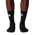 Calcetines The North Face Multi Sport Cushion en negro puestos en modelo, vista frontal de ambas piernas mostrando el logo bordado en gris claro sobre el puño acanalado.