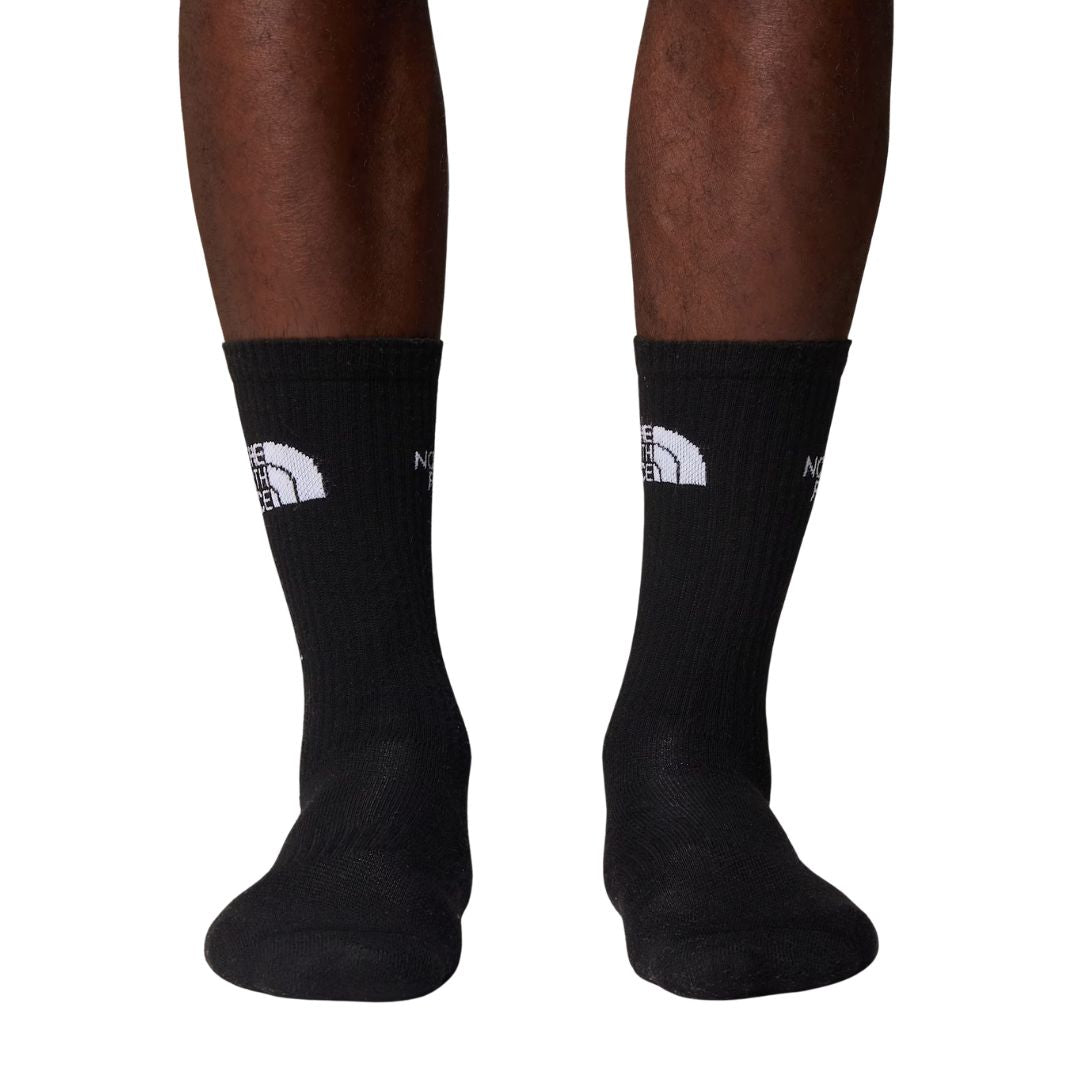 Calcetines The North Face Multi Sport Cushion en negro puestos en modelo, vista frontal de ambas piernas mostrando el logo bordado en gris claro sobre el puño acanalado.