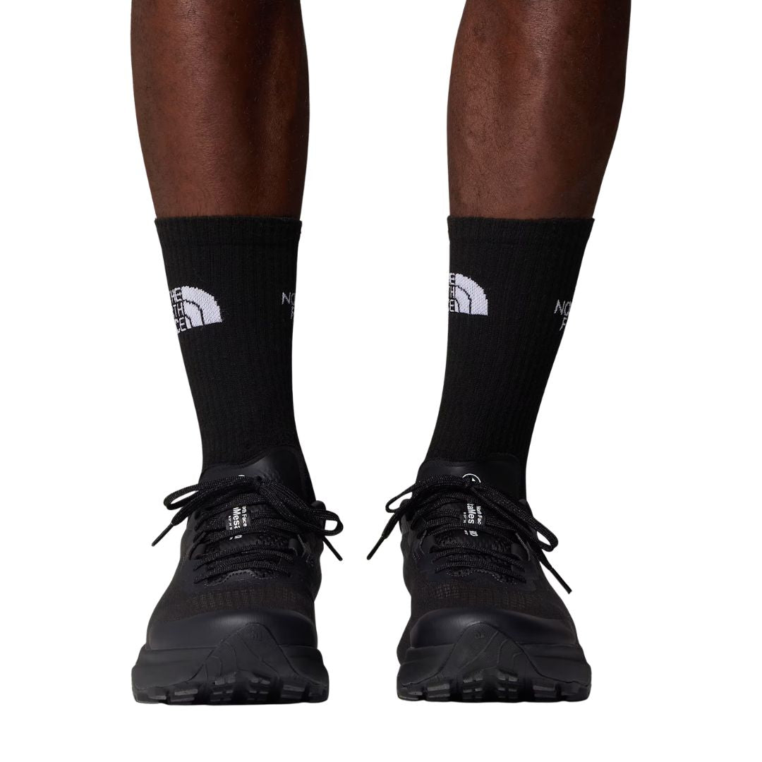 Calcetines The North Face Multi Sport Cushion en negro puestos en modelo con zapatillas de trail running negras, vista frontal mostrando el ajuste en el tobillo.