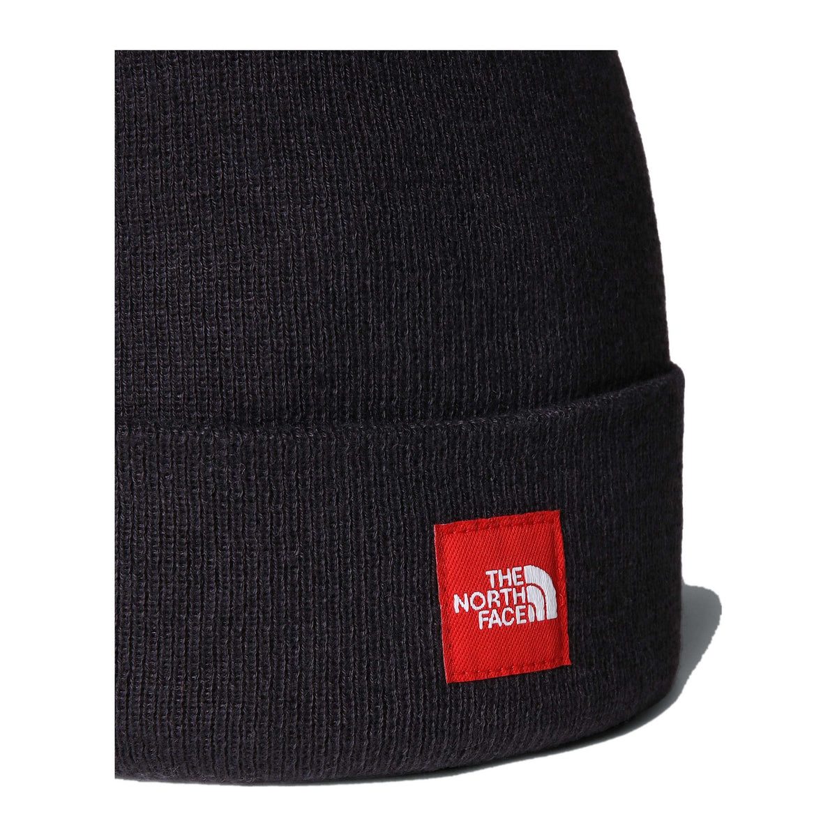 Detalle en primer plano del tejido de punto del gorro The North Face Red Box Beanie TNF Black y del parche rojo con el logo The North Face bordado sobre el borde vuelto