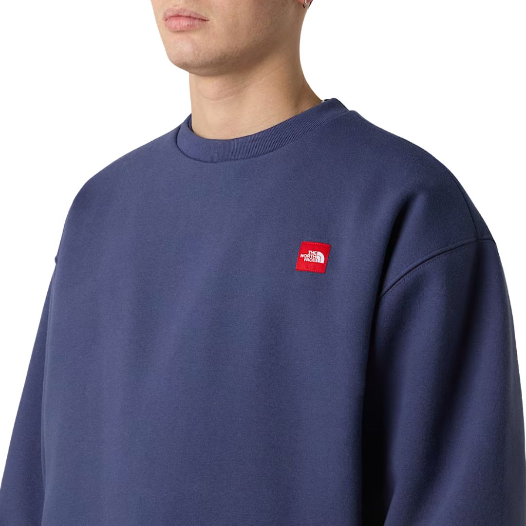 Detalle del pecho de la sudadera THE NORTH FACE Red Box Crew Lunar Blue con logotipo rojo bordado.