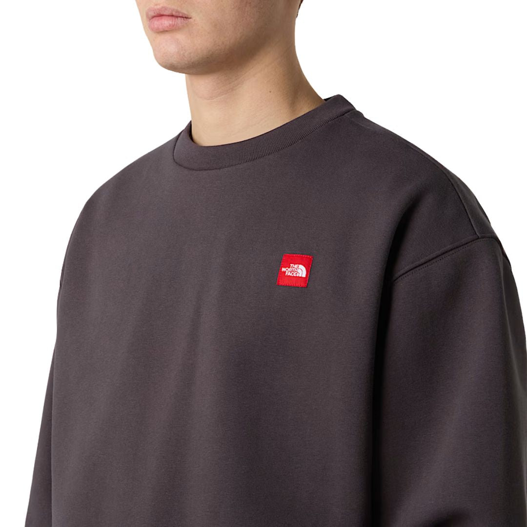 Sudadera The North Face Red Box Crew color Obsidian detalle en el pecho en modelo hombre.
