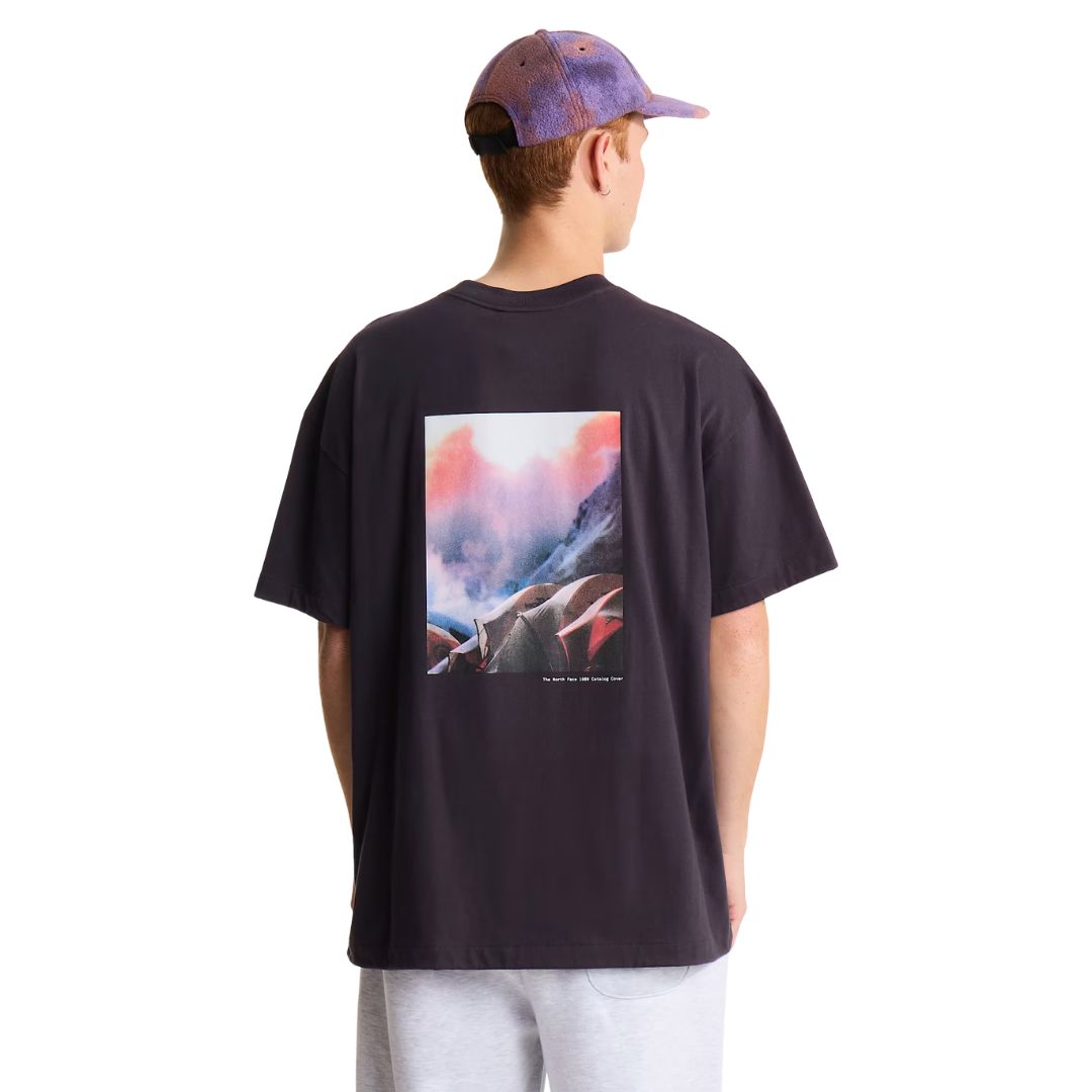 Camiseta The North Face Red Box oversize color obsidian, vista trasera de medio cuerpo sobre modelo con gorra, mostrando el estampado fotográfico central completo.