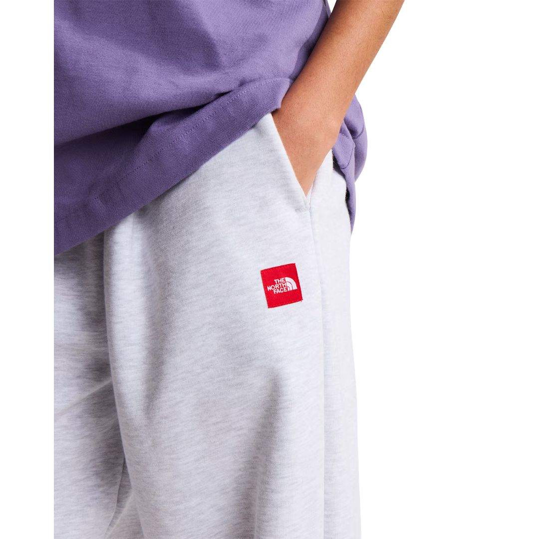 Detalle del bolsillo lateral del pantalón de chándal The North Face Red Box en gris jaspeado TFN Classic, con el parche rojo del logo bajo la costura.