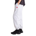 Pantalón de chándal The North Face Red Box en gris jaspeado TFN Classic, vista lateral de cuerpo completo con camiseta negra, mano en el bolsillo y parche rojo del logo en la cadera.
