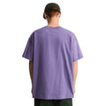 Vista trasera de la camiseta The North Face Redbox manga corta unisex color Grounded Plum, hombre con gorra verde mostrando el ajuste oversize desde atrás.