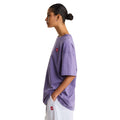 Camiseta The North Face Redbox manga corta unisex color Grounded Plum, mujer de perfil con la mano en el bolsillo, parche bordado rojo visible junto al brazo.