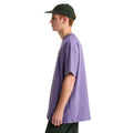 Camiseta The North Face Redbox manga corta unisex color Grounded Plum, hombre de perfil con gorra verde mostrando el ajuste oversize y el cuello de canalé.