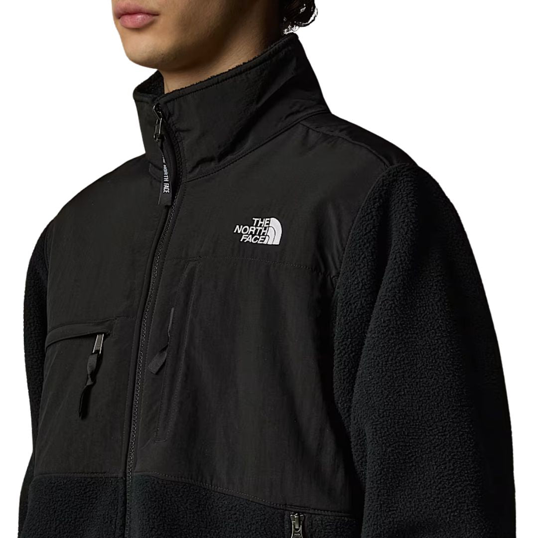 Primer plano lateral del pecho de la chaqueta The North Face Retro Denali en mostaza, con cremallera y logotipo bordado en blanco
