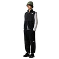 Modelo masculino con chaleco The North Face Retro Denali Vest en color negro, conjunto completo con pantalón a juego.