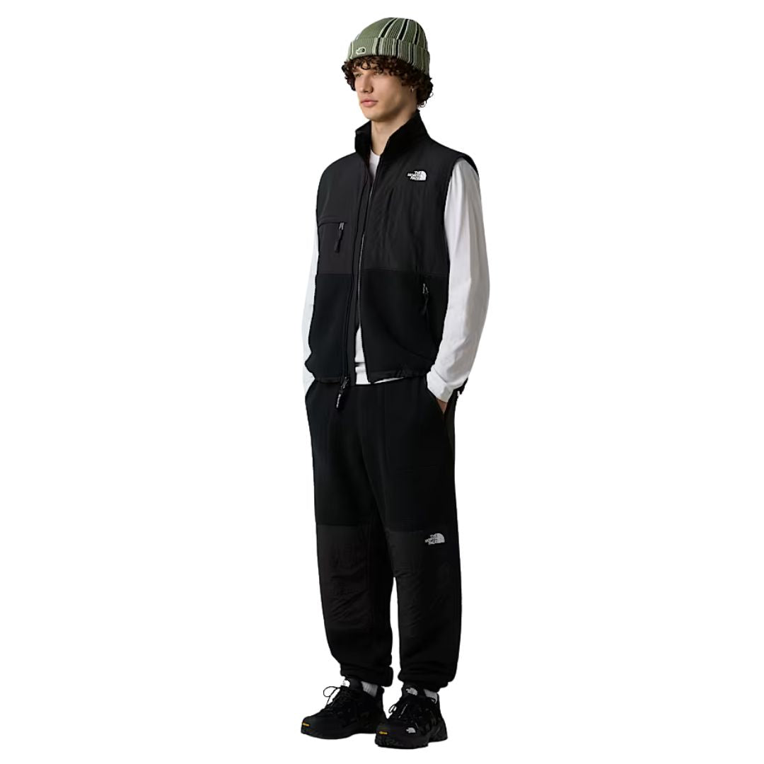 Modelo masculino con chaleco The North Face Retro Denali Vest en color negro, conjunto completo con pantalón a juego.