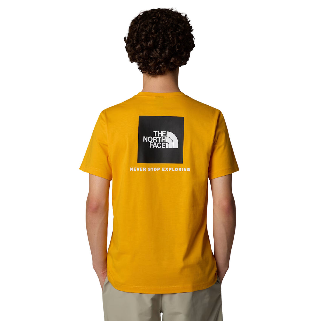 Hombre con la camiseta The North Face S/S Redbox Tee amarilla con el cuadro en negro y la leyenda "Never stop exploring"