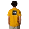 Hombre con la camiseta The North Face S/S Redbox Tee amarilla con el cuadro en negro y la leyenda 