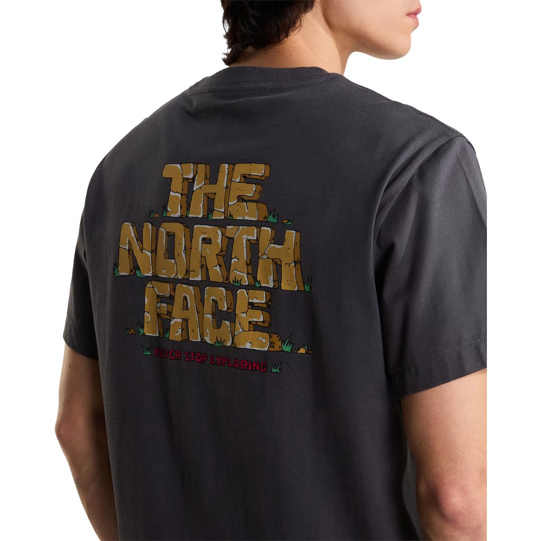Primer plano del estampado trasero de la camiseta The North Face Stone Logo RLX en gris antracita, mostrando el detalle del gráfico estilo bloques de piedra y "NEVER STOP EXPLORING".