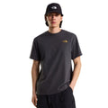 Camiseta The North Face Stone Logo RLX en gris antracita puesta en modelo hombre, vista frontal con gorra negra a juego, mostrando el logotipo pequeño en el pecho.