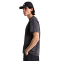 Camiseta The North Face Stone Logo RLX en gris antracita puesta en modelo hombre, vista lateral de perfil mostrando el corte holgado y la caída de la manga.