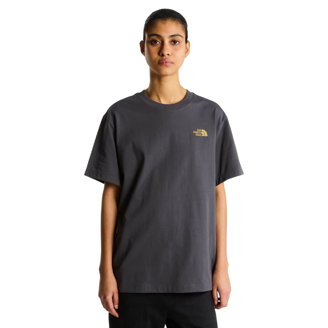 Camiseta The North Face Stone Logo RLX en gris antracita puesta en modelo mujer, vista frontal mostrando el logotipo pequeño estilo piedra en el pecho.