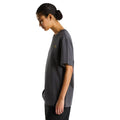 Camiseta The North Face Stone Logo RLX en gris antracita puesta en modelo mujer, vista lateral de perfil mostrando el corte holgado unisex.