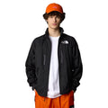 Hombre con la Chaqueta The North Face x Yinka Ilori Windshell Negra abierta y gorra naranja 