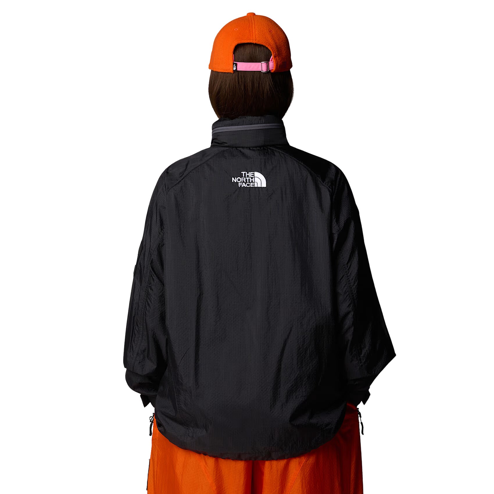 Mujer con la Chaqueta The North Face x Yinka Ilori Windshell Negra y gorra naranja espalda