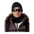 Modelo con gafas de sol y gorro oscuro lleva la braga The North Face Winter Seamless Reversible Neck Warmer TNF Black más baja alrededor del cuello, bajo una chaqueta con capucha de pelo