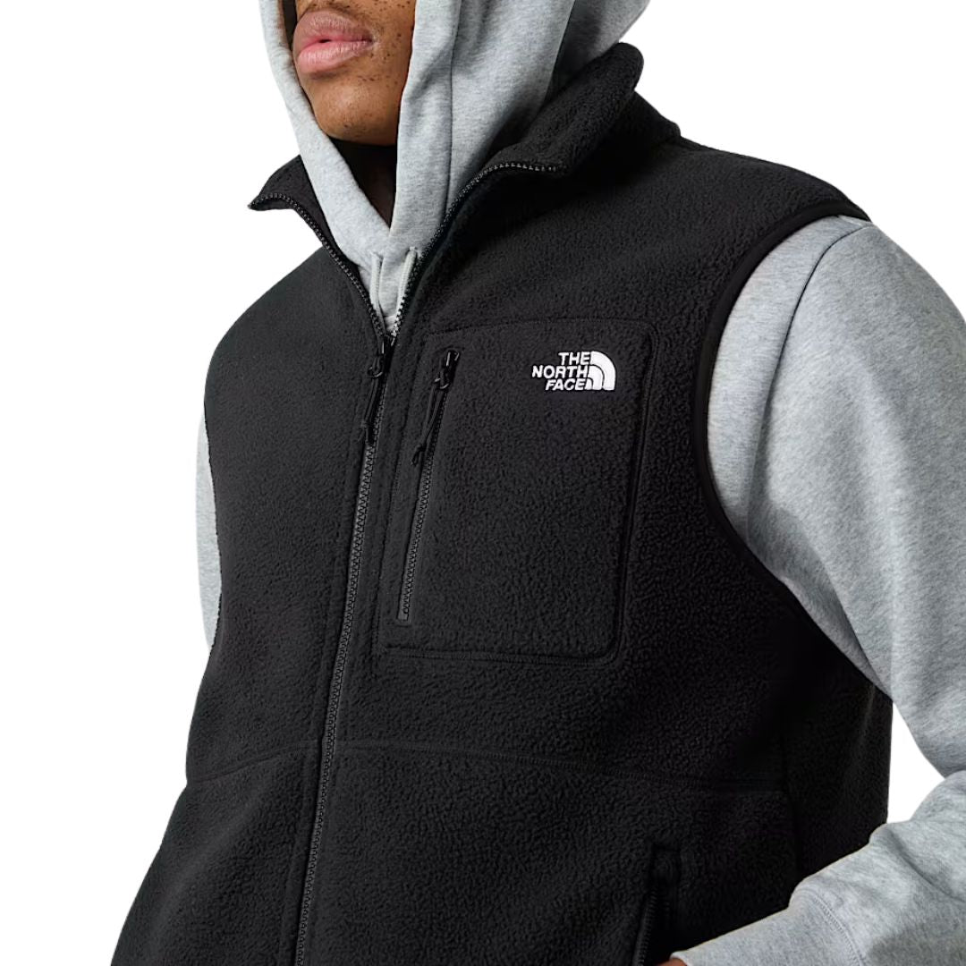 Vista lateral del chaleco The North Face Yumiori Vest en color negro, combinado con sudadera gris y pantalón verde.