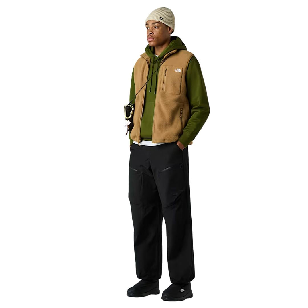 Conjunto completo de modelo llevando chaleco The North Face Yumiori Vest color Utility Brown combinado con sudadera verde y pantalón negro.