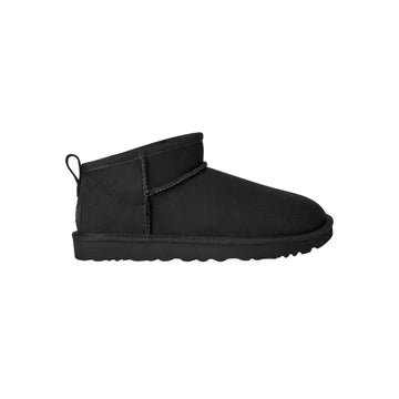 Bota UGG Classic Ultra Mini en color negro de perfil completo sobre fondo blanco, mostrando su silueta compacta de caña baja ideal para el uso diario.