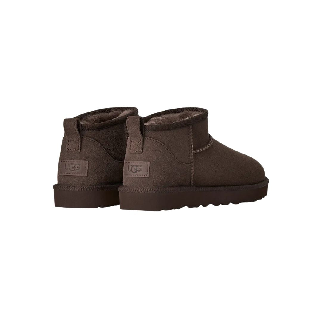 Par de botas UGG Classic Ultra Mini en color dusted cocoa vistas desde atrás en ángulo, mostrando la trabilla trasera, el contrafuerte y la suela flexible de goma.