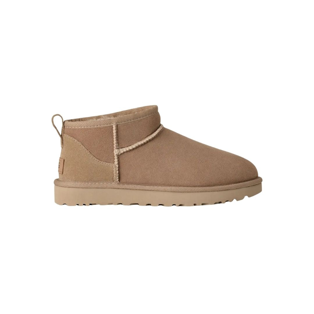 Bota UGG Classic Ultra Mini en color sand vista de perfil completo sobre fondo blanco, mostrando la silueta compacta de caña baja, ideal para el uso diario y para combinar con cualquier look.