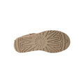 Suela de la bota UGG Classic Ultra Mini en color sand mostrando el dibujo direccional de la banda de rodadura y el logotipo UGG grabado en el talón de la suela.