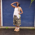 Mujer con zapatillas UGG Lowmel en color chestnut combinadas con pantalón camuflaje y top blanco, mostrando el estilo retro west coast del calzado en exterior.