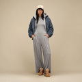 Mujer con zapatillas UGG Lowmel en color chestnut combinadas con chaqueta polar azul y conjunto gris, luciendo los cordones gruesos sueltos y el empeine de ante.
