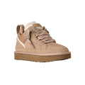 Vista en ángulo de tres cuartos de la zapatilla UGG Lowmel en color sand, destacando los cordones planos bicolor anudados y la lengüeta acolchada extragrande.